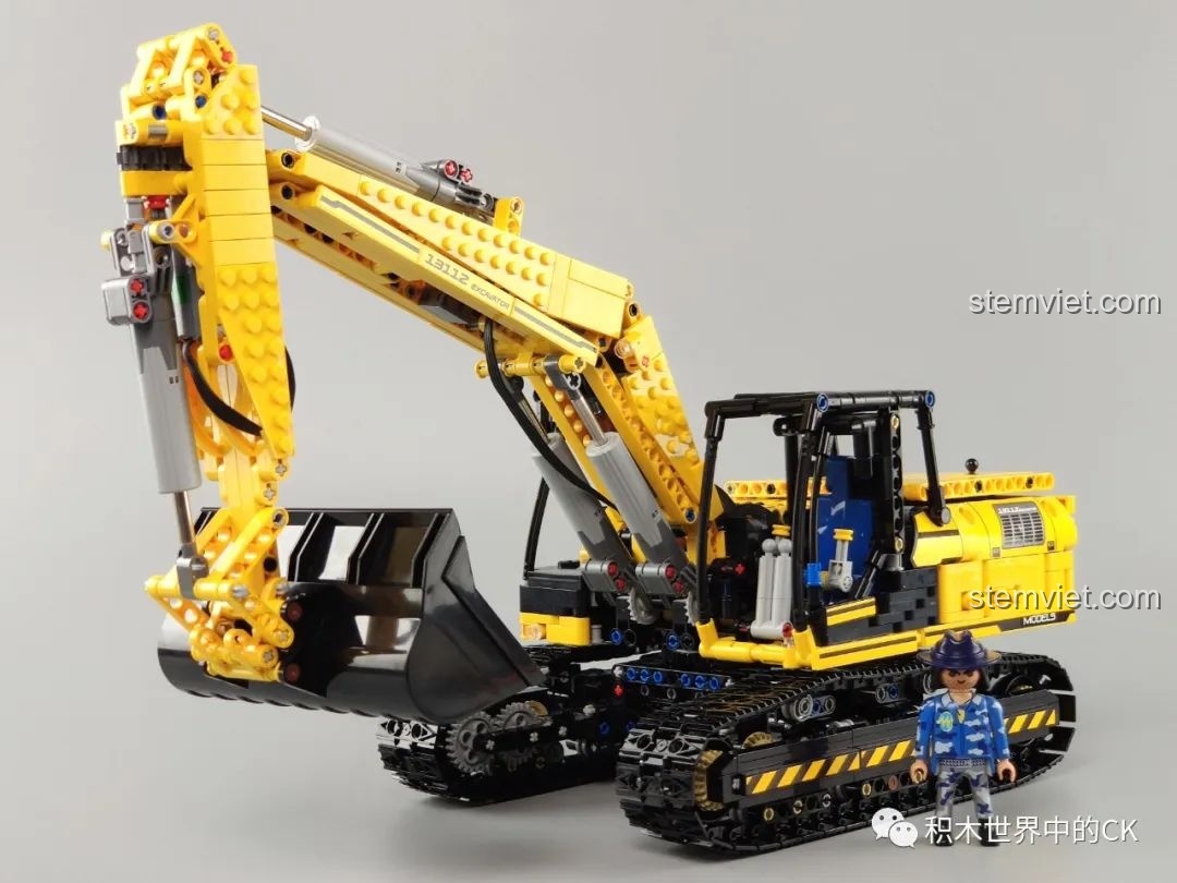 So sánh tỷ lệ kích thước giữa mô hình máy xúc Mould King 13112 và một nhân vật đồ chơi nhỏ.