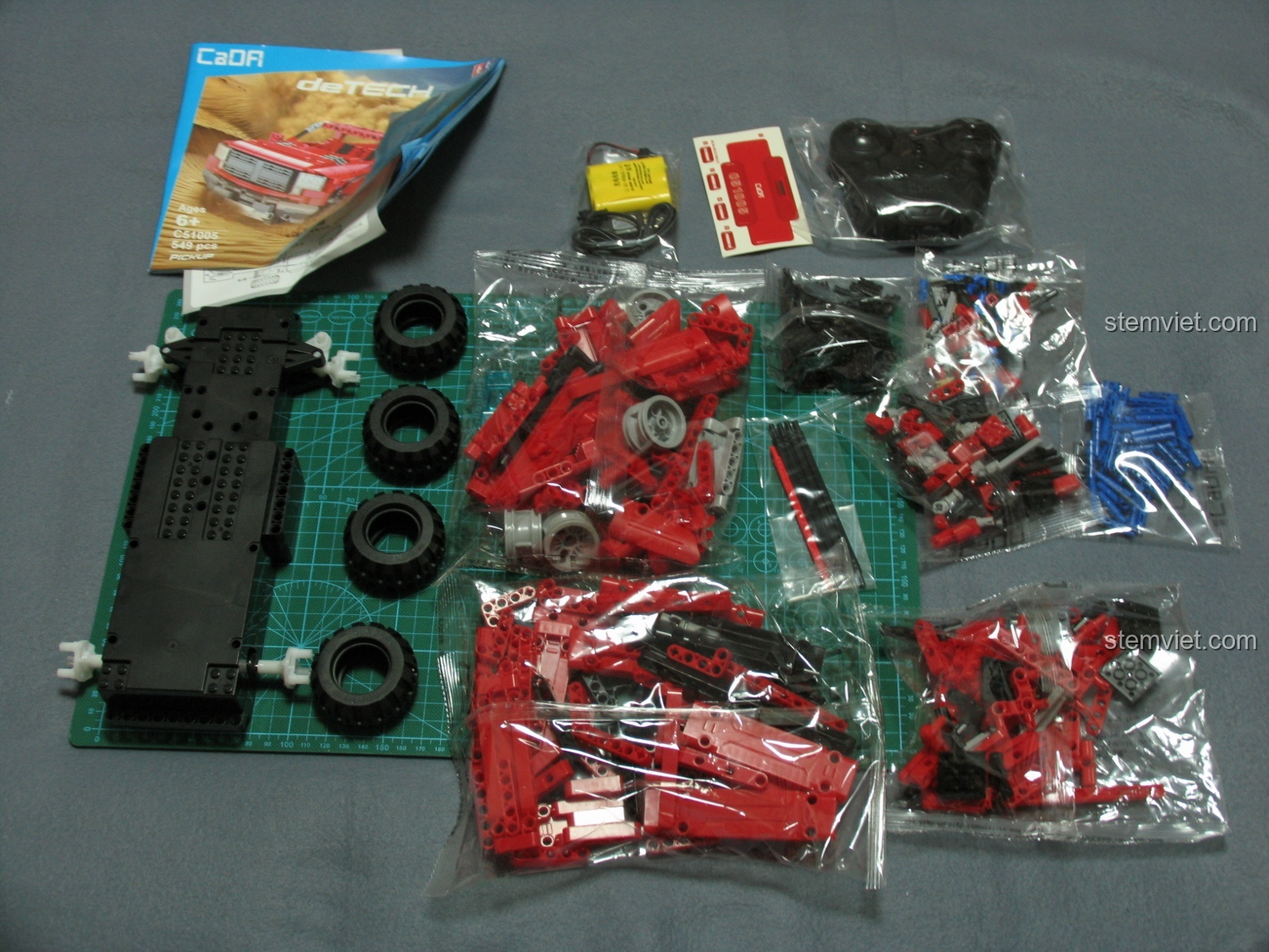 Toàn bộ linh kiện của bộ lắp ráp CaDA C51005 Xe Bán Tải Đỏ bao gồm các túi mảnh ghép, lốp xe, khung gầm, sách hướng dẫn và bộ điều khiển.