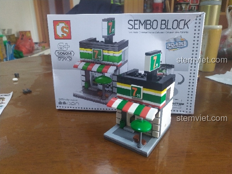 Ảnh chụp thành phẩm bộ lắp ghép Cửa hàng tiện lợi Holiday Street Sembo SD6014 bên cạnh vỏ hộp, thể hiện sự tương đồng.