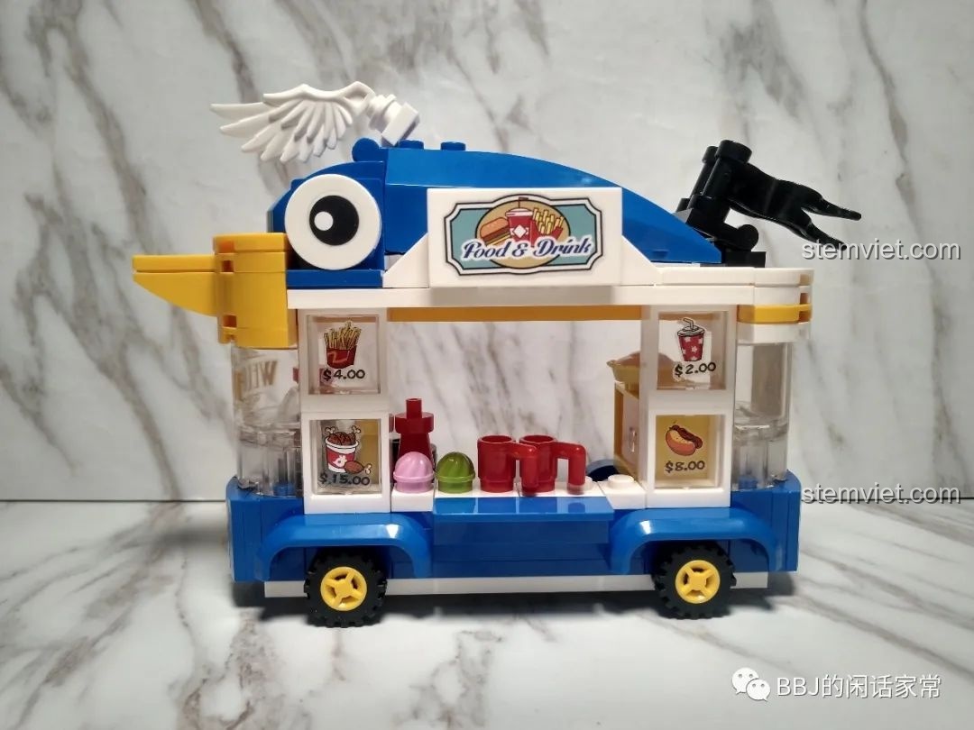 Toàn cảnh xe bán đồ uống của Vịt Donald nhìn từ bên cạnh, nổi bật với thiết kế hình con chim màu xanh.