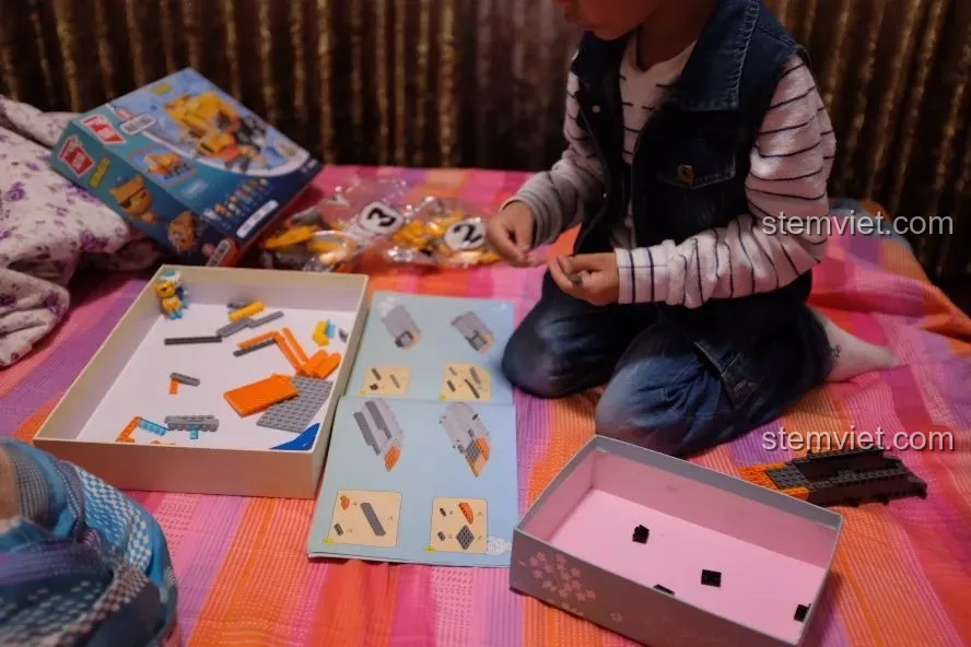 Bé trai 5 tuổi đang tập trung xem sách hướng dẫn lắp ráp bộ đồ chơi Tàu ngầm của Thuyền trưởng Barnacles QMAN 3704.