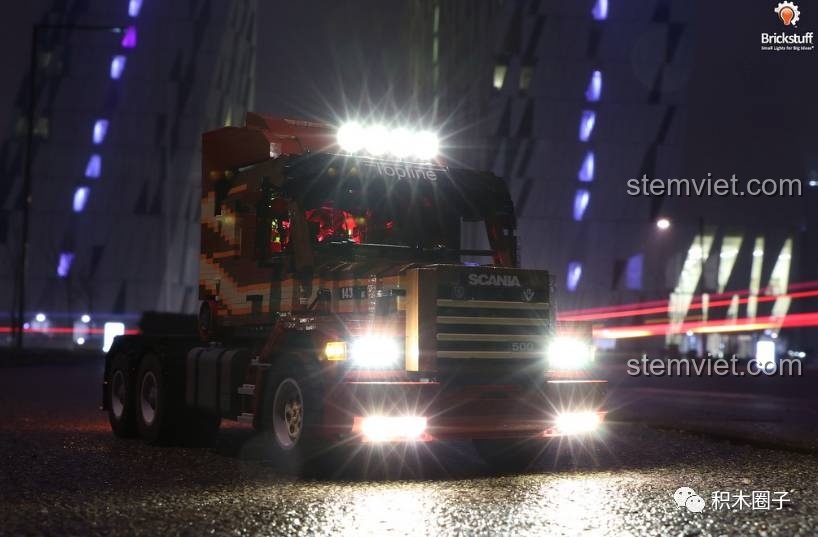 Xe tải mô hình Scania với đèn pha và đèn nóc sáng chói trong đêm, thể hiện trải nghiệm Xingbao 07401 rất chân thực.