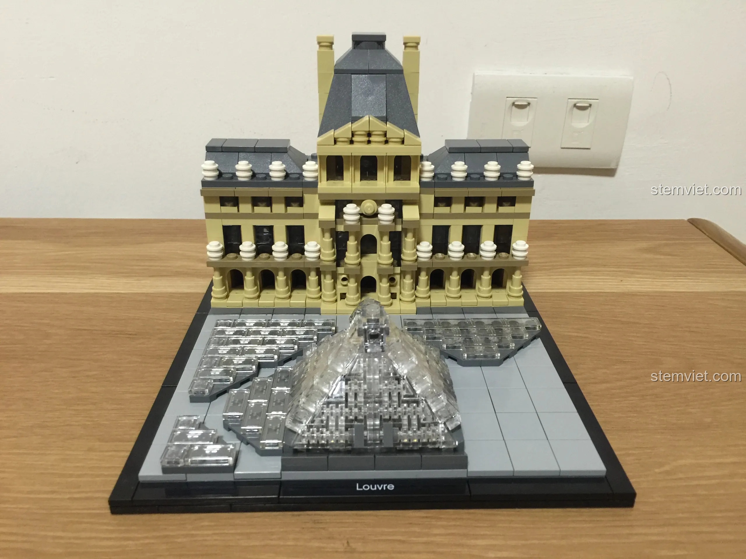 Toàn cảnh mô hình LEGO Architecture 21024 Louvre hoàn chỉnh được trưng bày trên bàn gỗ, một vật trang trí tinh tế.