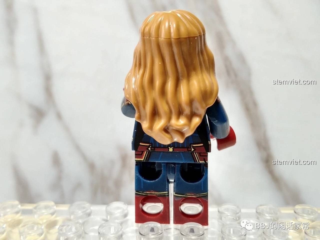 Ảnh chụp phía sau của Minifigure Captain Marvel XINH X0256, cho thấy mái tóc vàng và chi tiết in sau lưng.