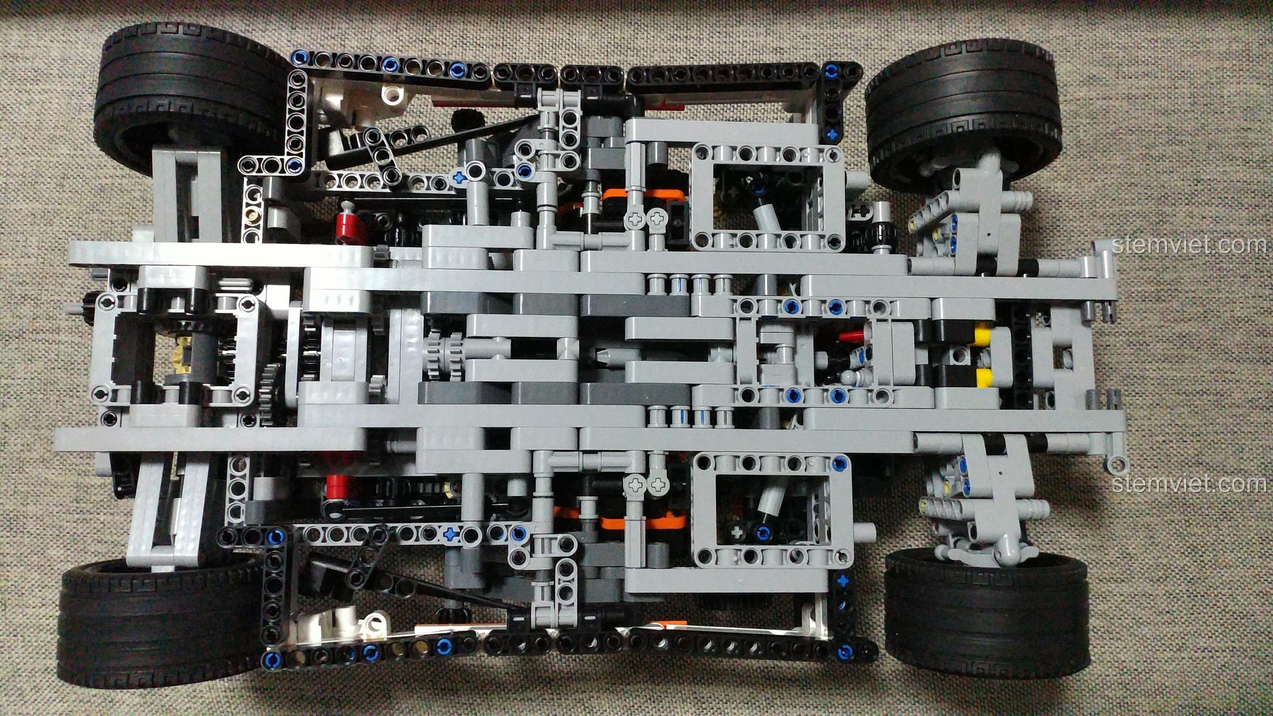 Khung xe YILE 915A đang dần hoàn thiện với ghế ngồi màu cam đen và hệ thống lái, một món đồ chơi lắp ráp hấp dẫn cho con trai.