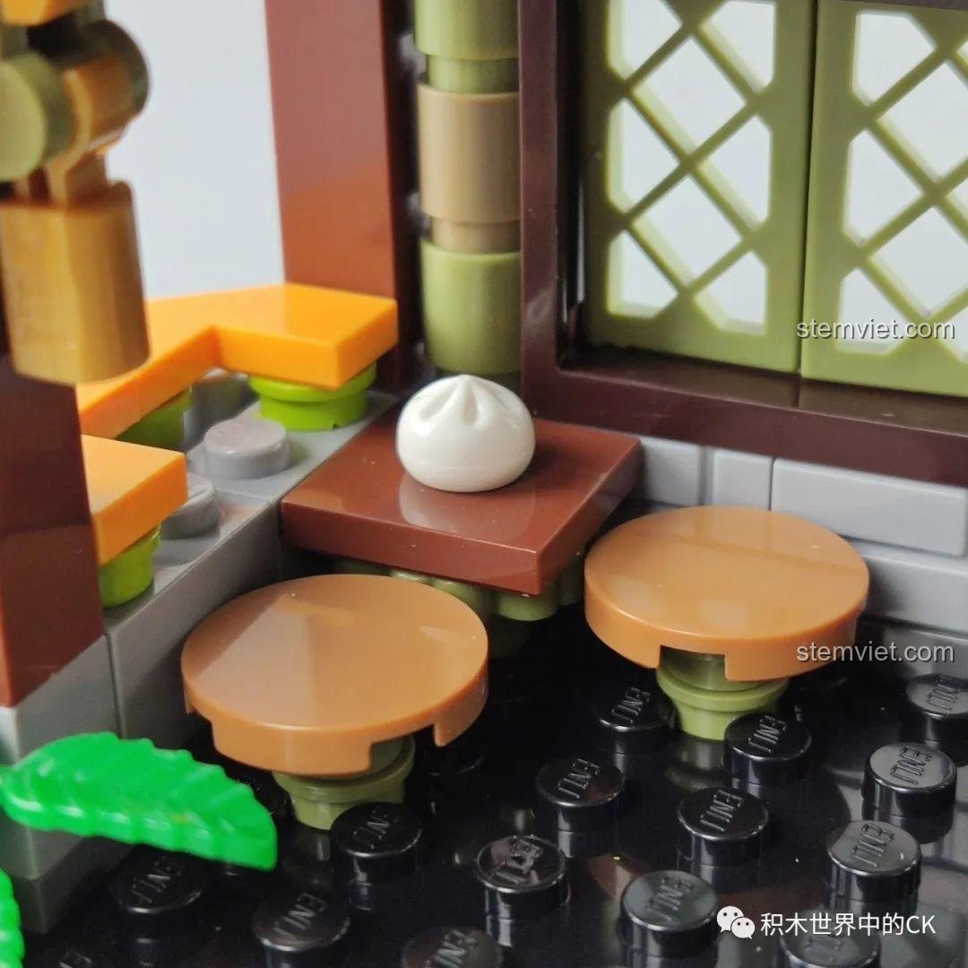 Khu vực bàn ghế khách ngồi trong mô hình Tiệm Bánh Bao Vô Song QMAN 72012, tạo không gian ăn uống.