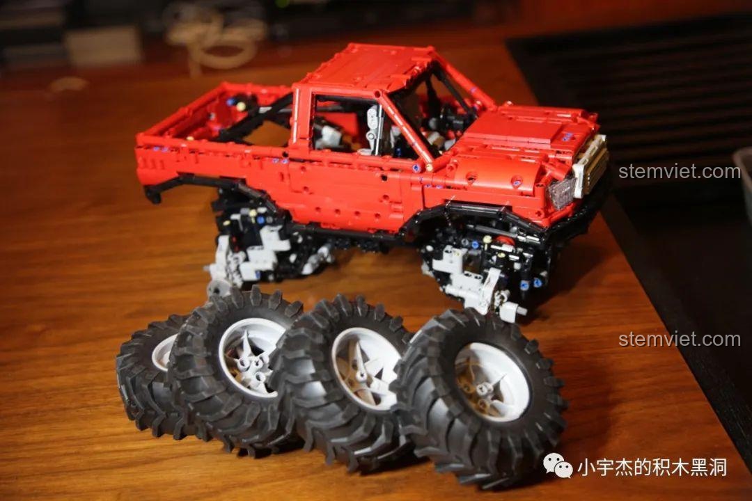 Bốn bánh xe khổng lồ của bộ lắp ráp Happy Build XQ1212D được đặt cạnh mô hình xe đã hoàn thiện phần thân.