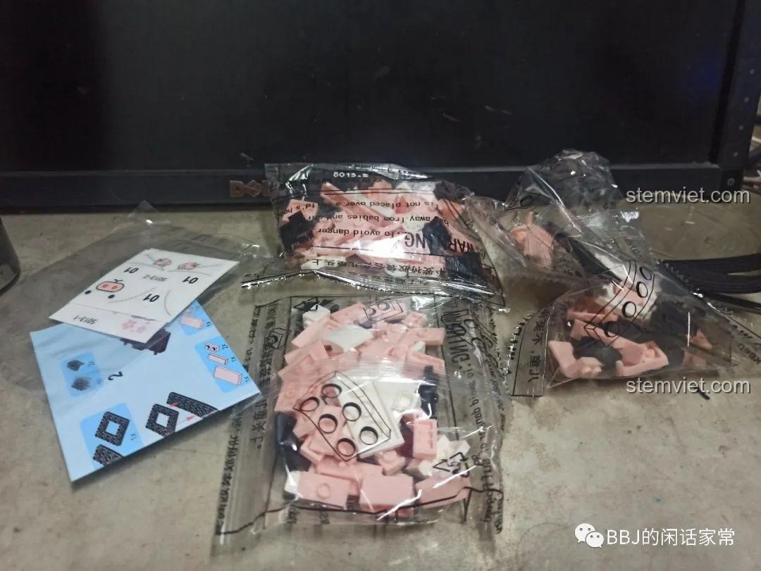 Toàn bộ các chi tiết bên trong hộp đồ chơi SY 5013, bao gồm các túi gạch, sách hướng dẫn và sticker trang trí.