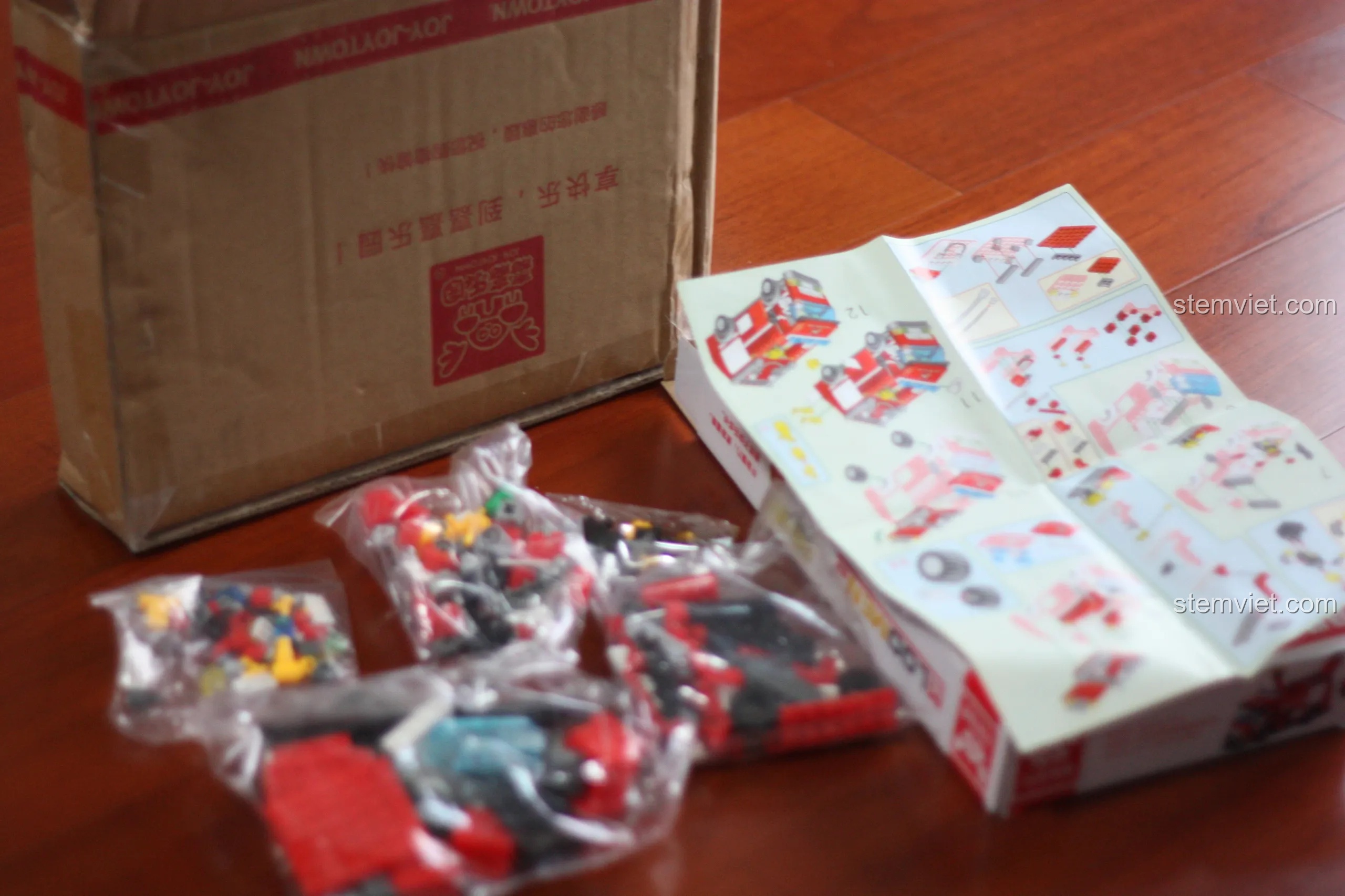 Toàn bộ các chi tiết bên trong hộp đồ chơi lắp ghép Xe Cứu Hỏa Thành Phố KAZI, bao gồm các túi và sách hướng dẫn.