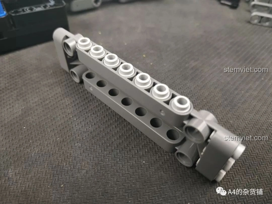 Một phần khung xe đang được lắp ráp, cho thấy các mảnh ghép Technic màu xám và các chốt xanh dương của bộ SEMBO 703940.