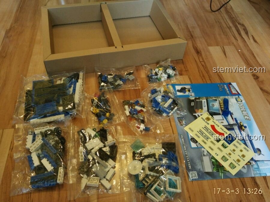 Các túi mảnh ghép, sách hướng dẫn và bộ sticker của bộ lắp ráp GUDI 9316 Xe Cảnh Sát Di Động được sắp xếp gọn gàng.