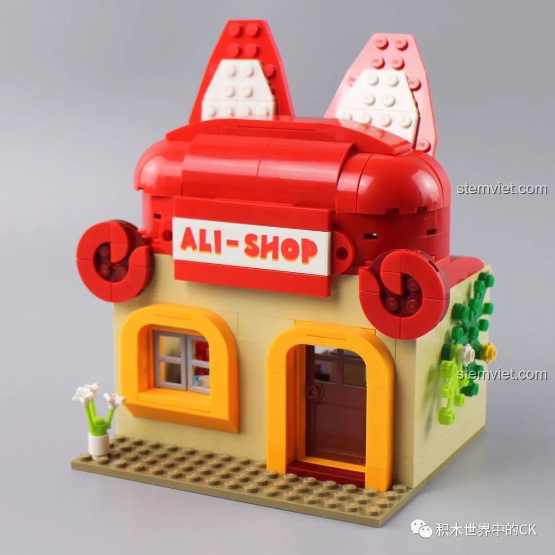 Nhân vật A-li và Gấu đứng cạnh mô hình Cửa hàng A-li của bộ QMAN 3901.