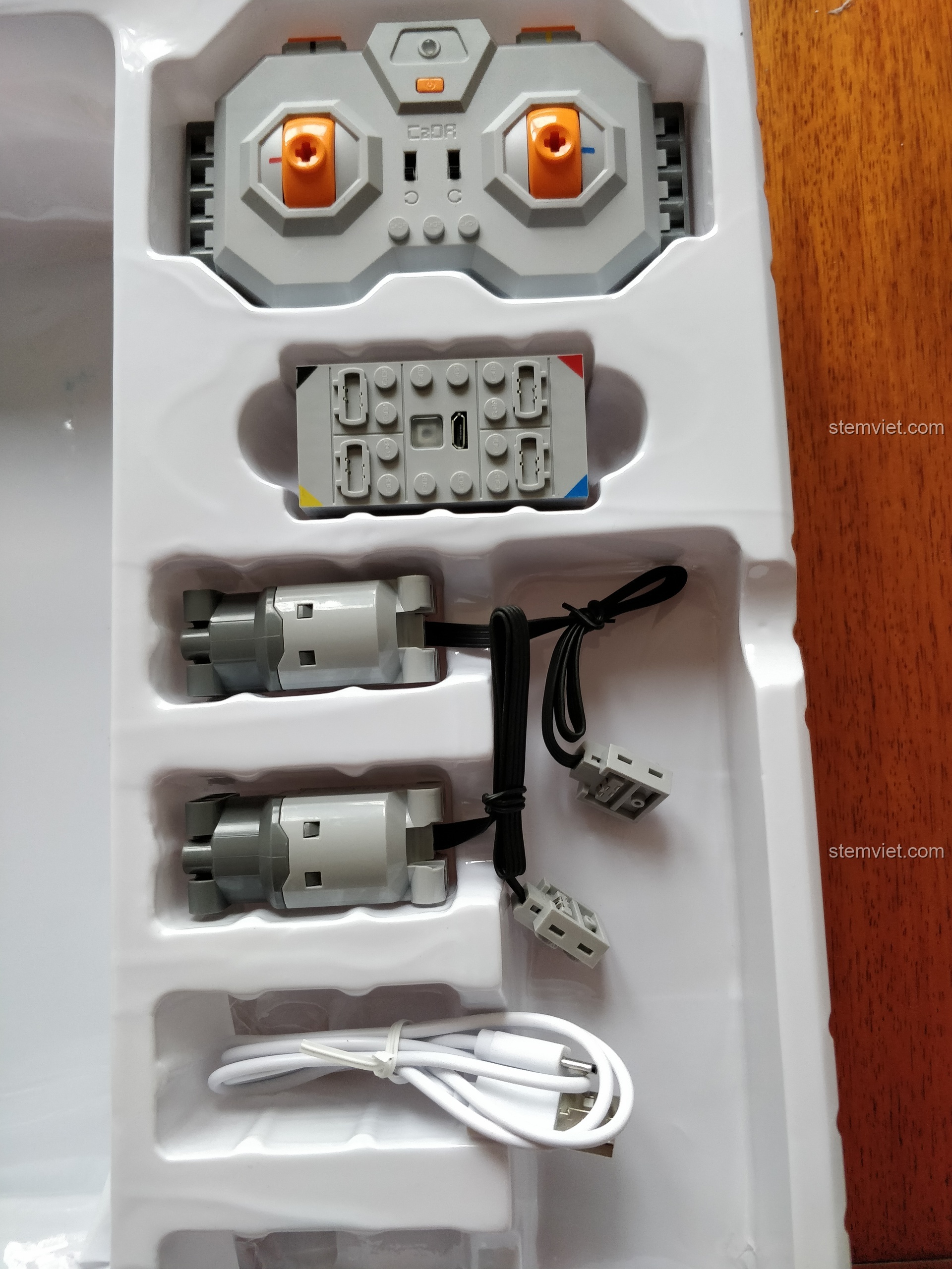 Bộ linh kiện điện tử của bộ lắp ráp Máy Xúc Bánh Xích Điều Khiển Từ Xa 51057, bao gồm động cơ, hộp pin, và tay cầm.