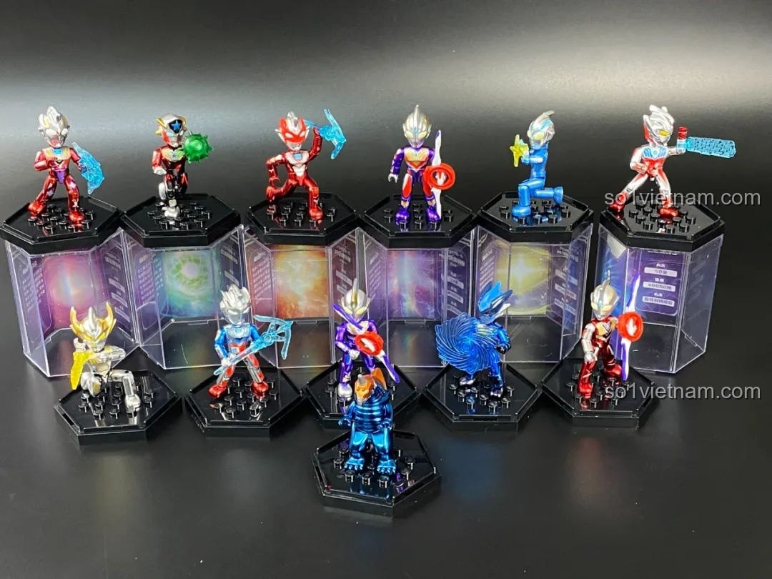 Một bộ sưu tập lớn các figure Ultraman Qman được đặt trên các đế trưng bày hình lục giác.