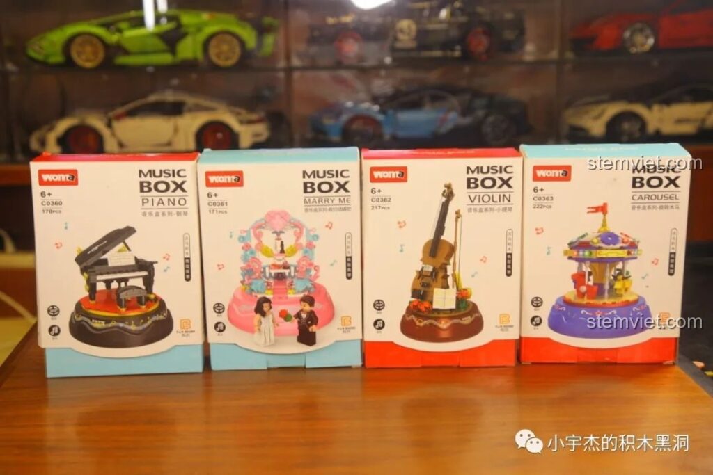 Bốn hộp sản phẩm của bộ sưu tập hộp nhạc WOMA C0360-C0363, gồm Piano, Marry Me, Violin và Carousel, xếp cạnh nhau trên bàn gỗ.