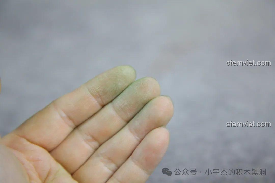 Bột màu xanh từ các chi tiết sơn phun dính lại trên đầu ngón tay.