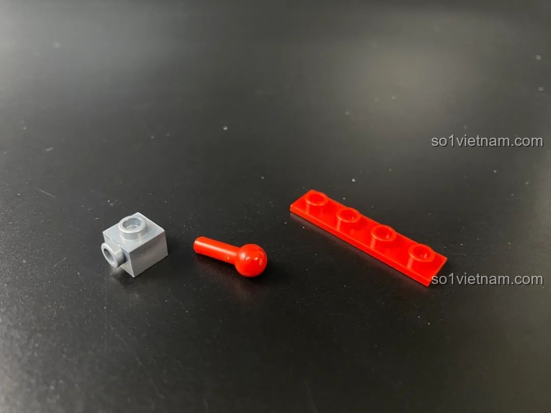 Các chi tiết khớp nối nhỏ của Qman, bao gồm một khối xám, một khớp bi đỏ và một thanh gạch đỏ.