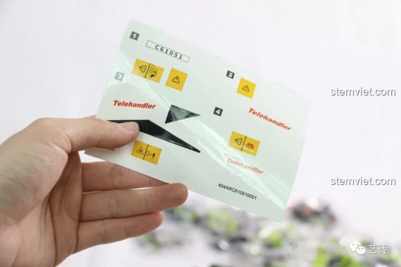 Tờ decal dán cho mô hình Xe Nâng Gắp Đa Năng C61051, bao gồm các logo và ký hiệu cảnh báo.