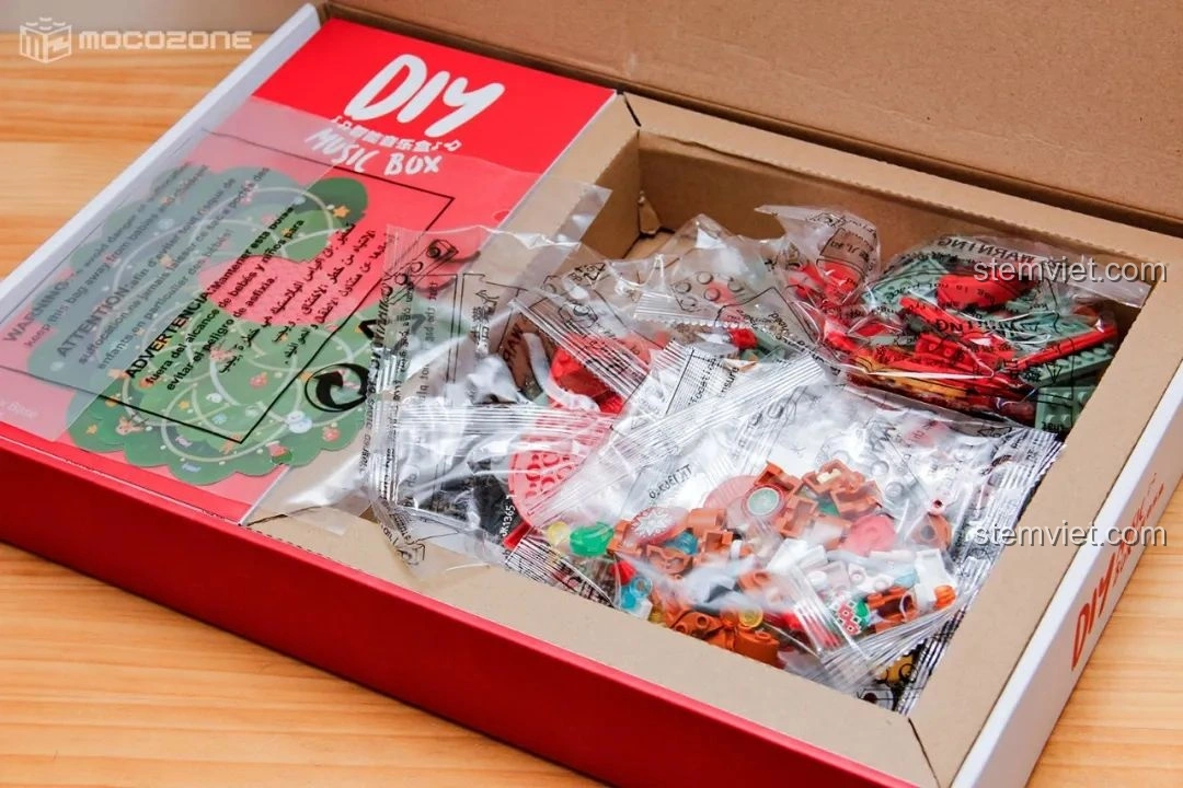 Bên trong hộp đồ chơi Hộp nhạc Giáng Sinh Xoay Tự Động JAKI JK1365 với các túi mảnh ghép được đóng gói cẩn thận, sẵn sàng cho việc lắp ráp.