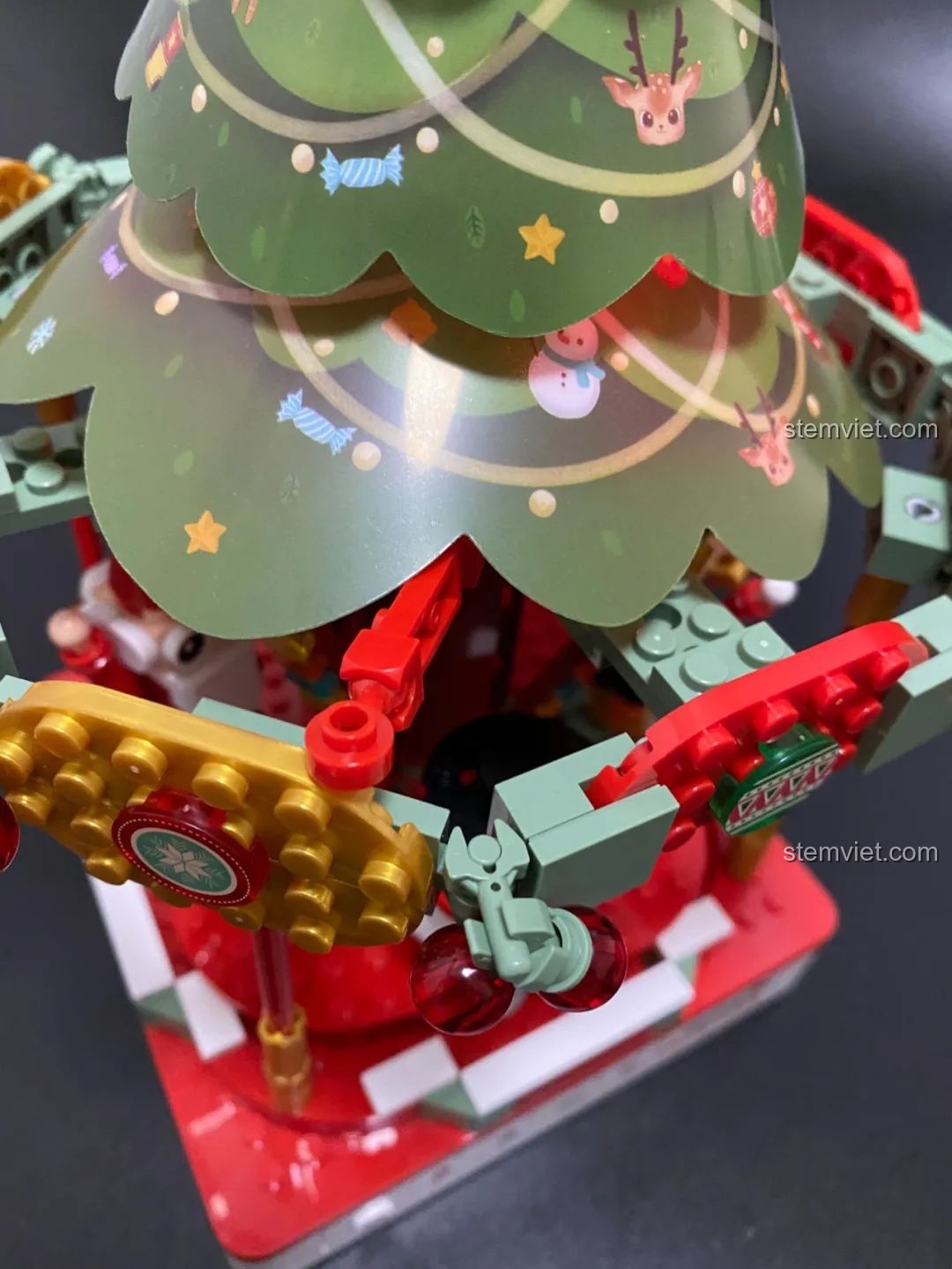 Cơ chế ẩn giấu bên dưới cây thông của Hộp nhạc Giáng Sinh Xoay Tự Động JAKI JK1365, điều khiển đèn phát sáng. Đồ chơi lắp ráp Giáng Sinh có nhạc.