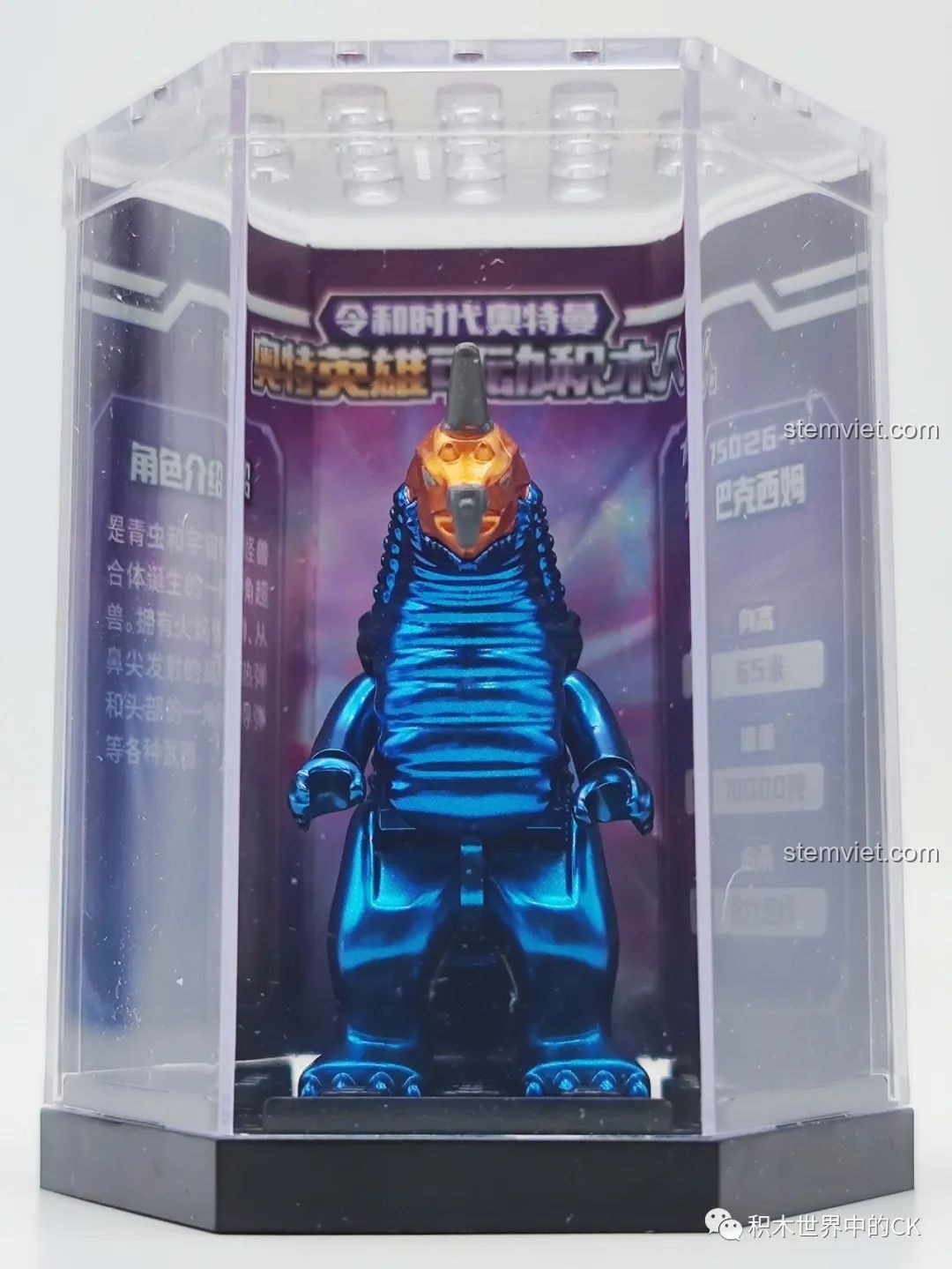 Mô hình quái vật Baxim 75026-11 được trưng bày trong hộp mica, kèm thông tin nhân vật. Cảm nhận QMAN 26 Ultraman.