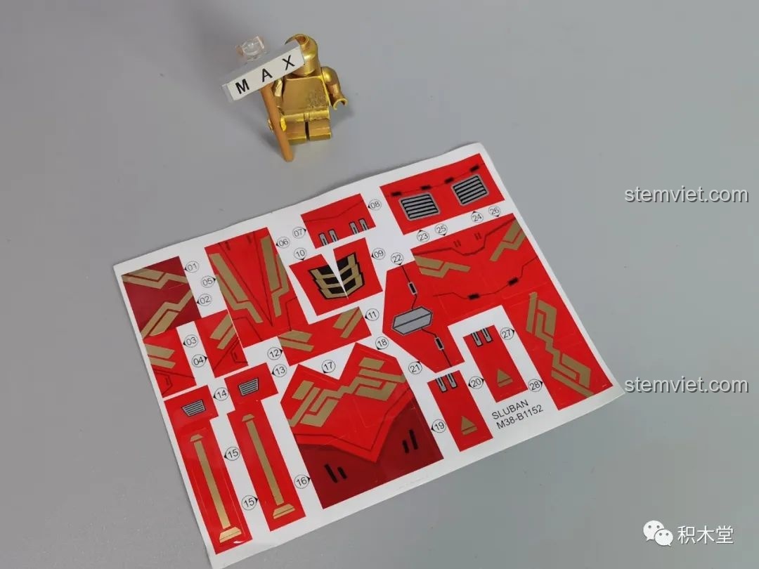 Tờ sticker đi kèm bộ lắp ráp Sluban M38-B1152 Robot Cơ Giáp Quang Kích Athena, với nhiều họa tiết trang trí màu đỏ và vàng.