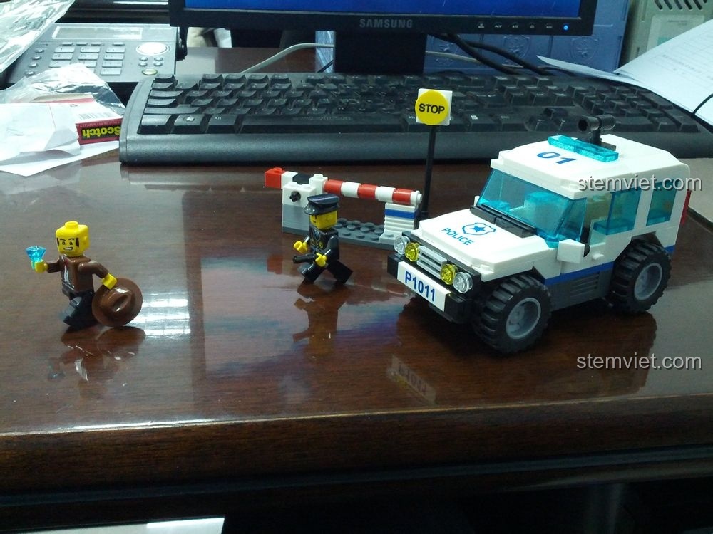 Mô hình Xe Tuần Tra Cảnh Sát WANGE 51011 đã hoàn thành, cùng với minifigures cảnh sát và tên cướp, rào chắn và biển báo.