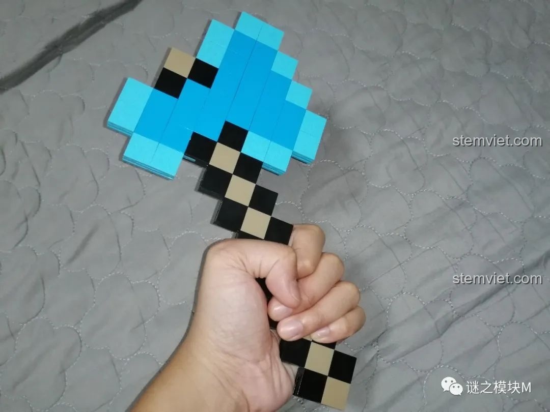 Một bàn tay đang cầm chiếc rìu kim cương từ bộ lắp ráp RENZAIMA 733, cho thấy kích thước thực tế.