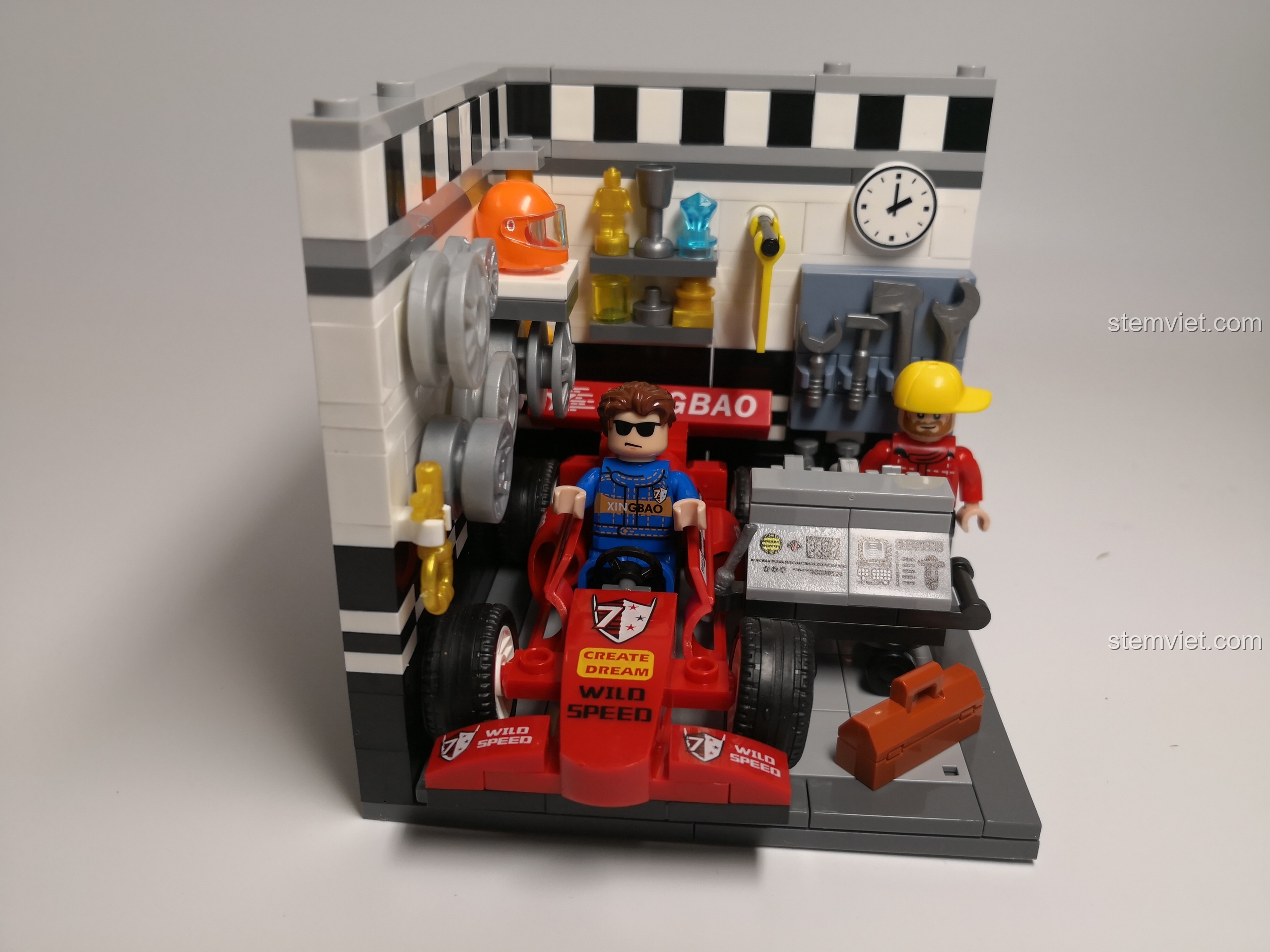 Cận cảnh các chi tiết trong Gara Đua xe, bao gồm lốp xe treo tường, dụng cụ sửa chữa và động cơ đang được bảo trì.