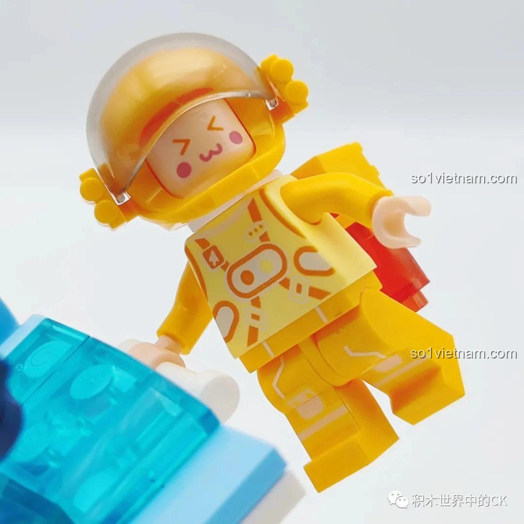 Cận cảnh phi hành gia vàng của bộ đồ chơi WISE BLOCK HA390213, với biểu cảm vui vẻ, đôi mắt nhắm và bộ đồ phi hành gia màu vàng tươi.