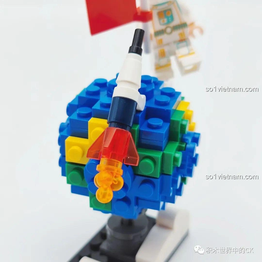 Cận cảnh tên lửa nhỏ và quả địa cầu mini với các mảnh ghép màu xanh, vàng, xanh lá, một phần của mô hình Flying Away from Earth trong bộ đồ chơi WISE BLOCK HA390213.