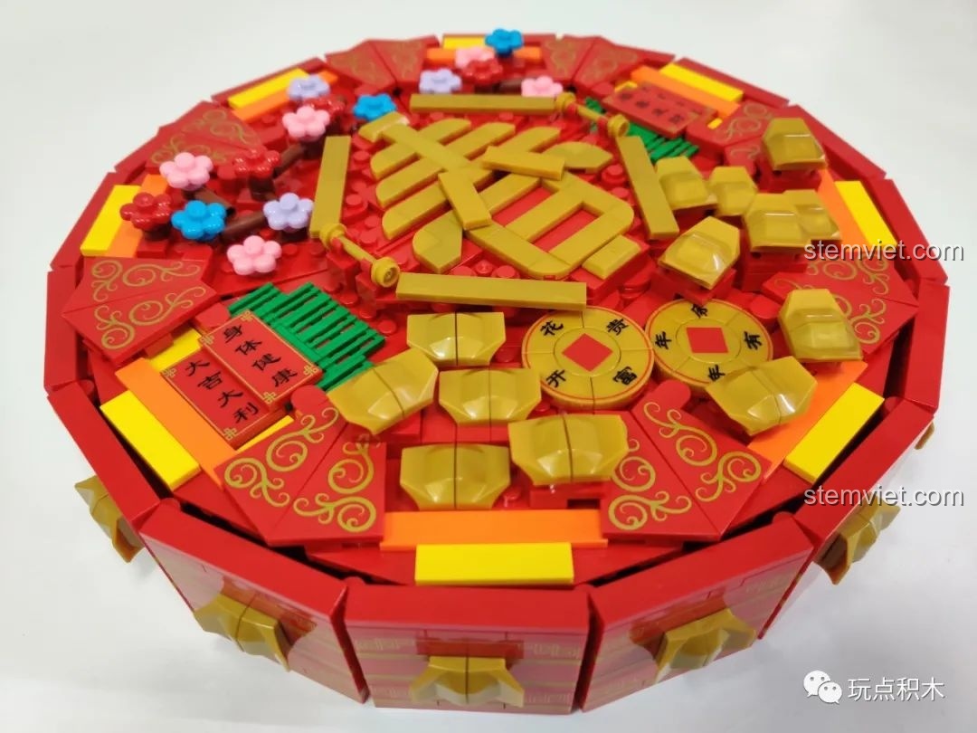 Cận cảnh chi tiết trang trí trên nắp hộp WOMA C.9122 với hoa mai, hoa đào và đồng tiền vàng.