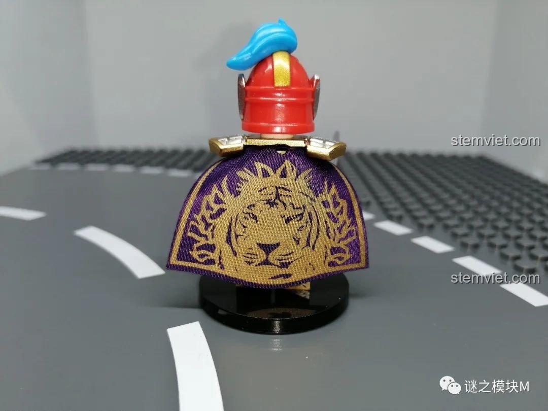 Cận cảnh chi tiết áo choàng của minifigure Chu Du, in hình đầu hổ màu vàng trên nền vải tím, thể hiện sự sang trọng.