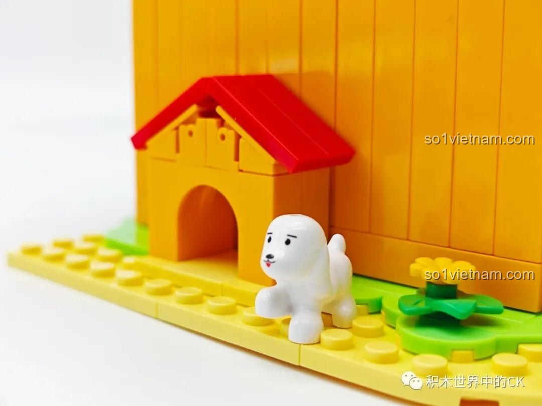 Cận cảnh chú chó nhỏ màu trắng và chuồng chó bên cạnh mô hình Tiệm đồ ngọt Maruko, tăng thêm sự sinh động.