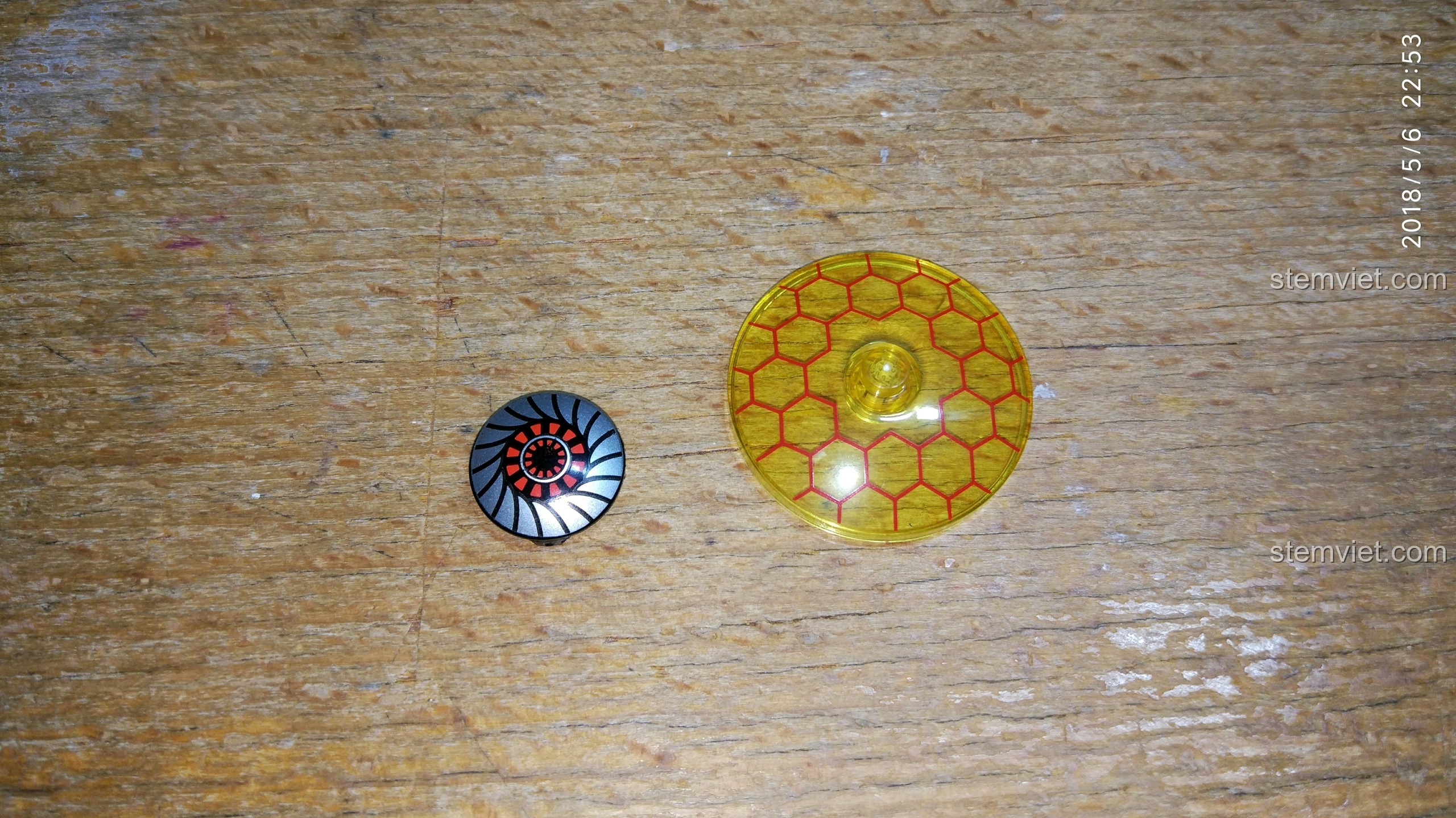 Hai chi tiết in hình tròn, một là khiên năng lượng màu vàng và một là họa tiết máy móc màu đen đỏ.