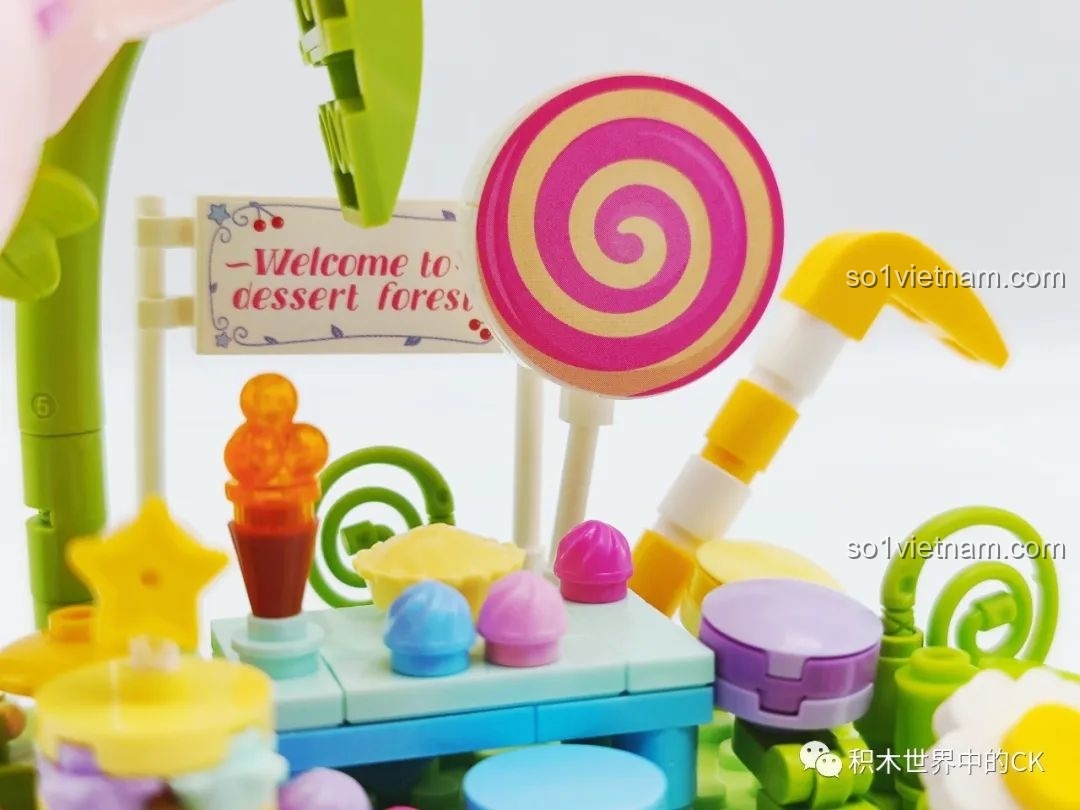 Cận cảnh chi tiết cây kẹo mút xoắn ốc và biển chào 'Welcome to dessert forest' trong mô hình.