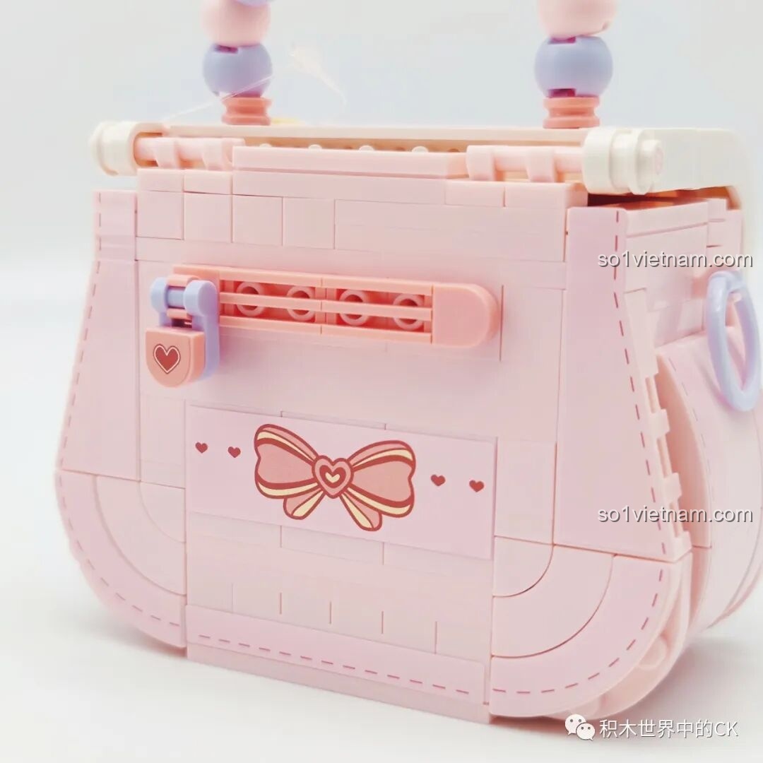 Cận cảnh khóa cài hình trái tim và họa tiết nơ ở mặt sau túi xách Wekki 516909.