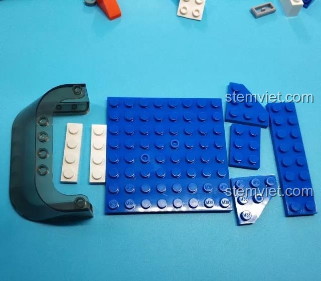 Các mảnh ghép màu xanh và trắng cùng kính chắn gió trong suốt để lắp ráp cabin tàu cảnh sát Sluban M38-B0657.