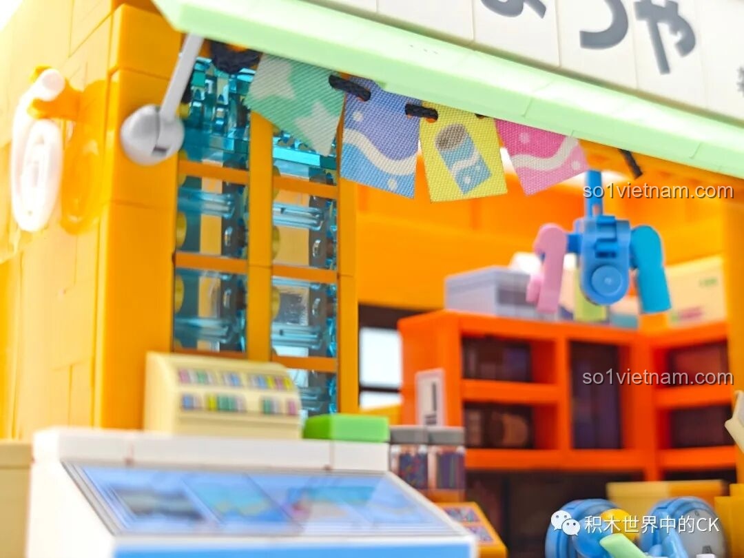 Cận cảnh chi tiết mái hiên với dây cờ và các món đồ chơi treo trang trí của Tiệm Tạp Hóa Maruko.