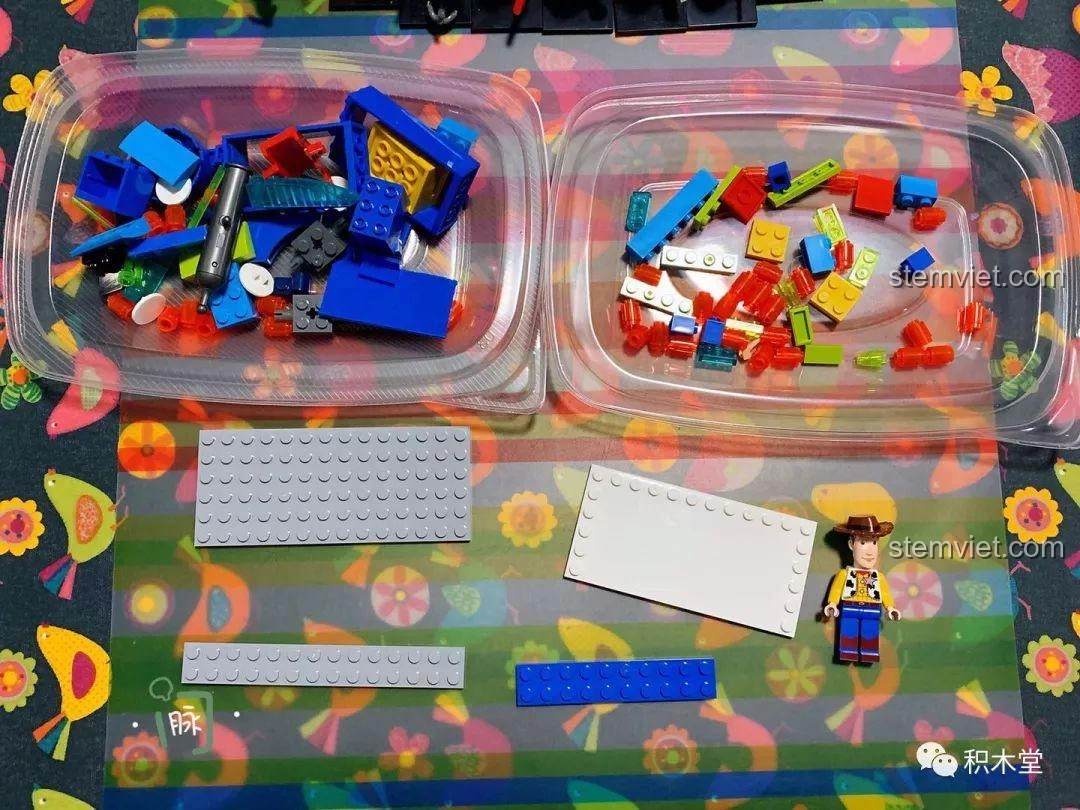 Các mảnh ghép của bộ lắp ráp Trò Chơi Bắn Bia của Woody, được phân loại trong hai hộp nhựa, sẵn sàng để lắp ráp.