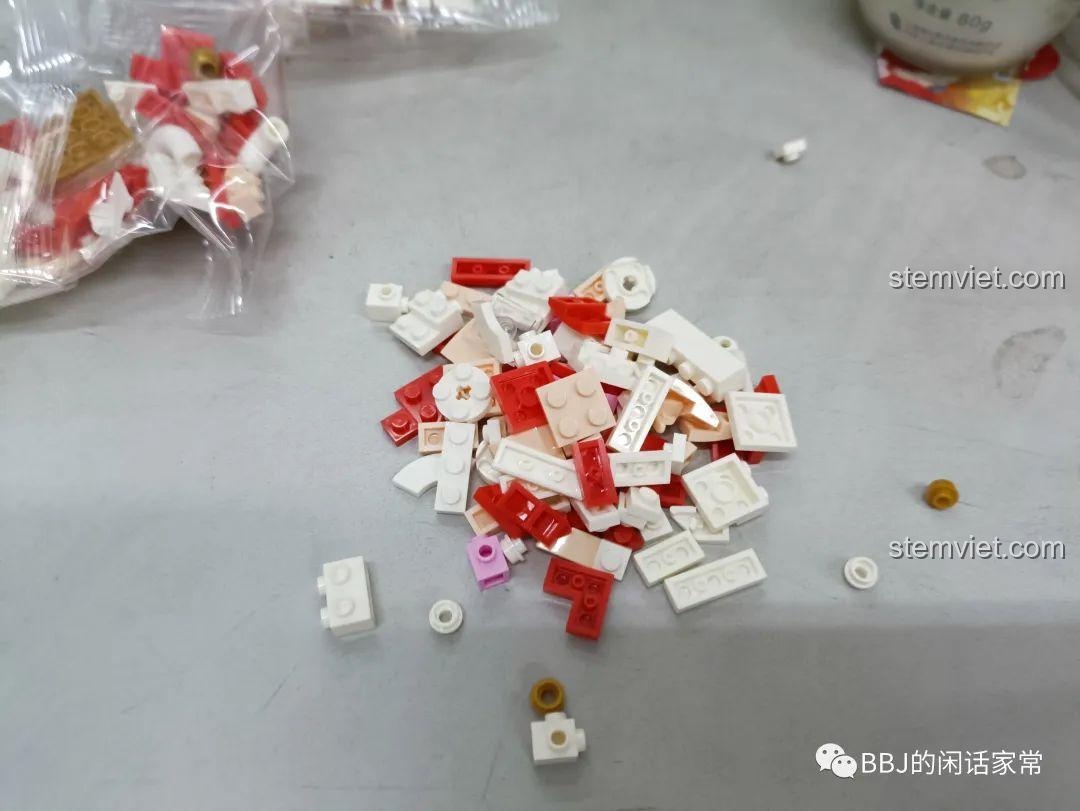 Các chi tiết mini block màu trắng, đỏ và vàng của bộ lắp ráp Xiao Meng Ji 2053 Mèo Thần Tài được đổ ra để chuẩn bị lắp.