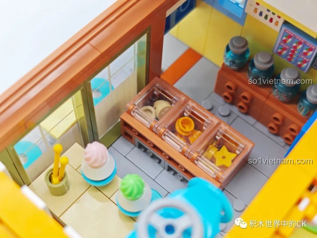 Cận cảnh quầy hàng với các khay đựng topping và ly kem trong mô hình Tiệm đồ ngọt Maruko.