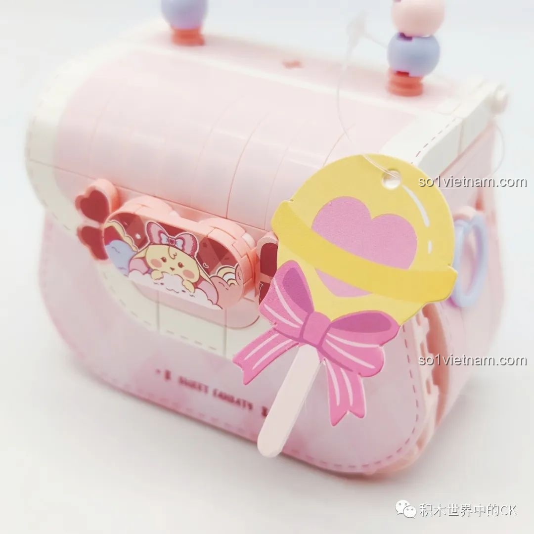 Cận cảnh tag trang trí hình que kẹo mút trái tim màu vàng và hồng trên túi xách Wekki 516909.