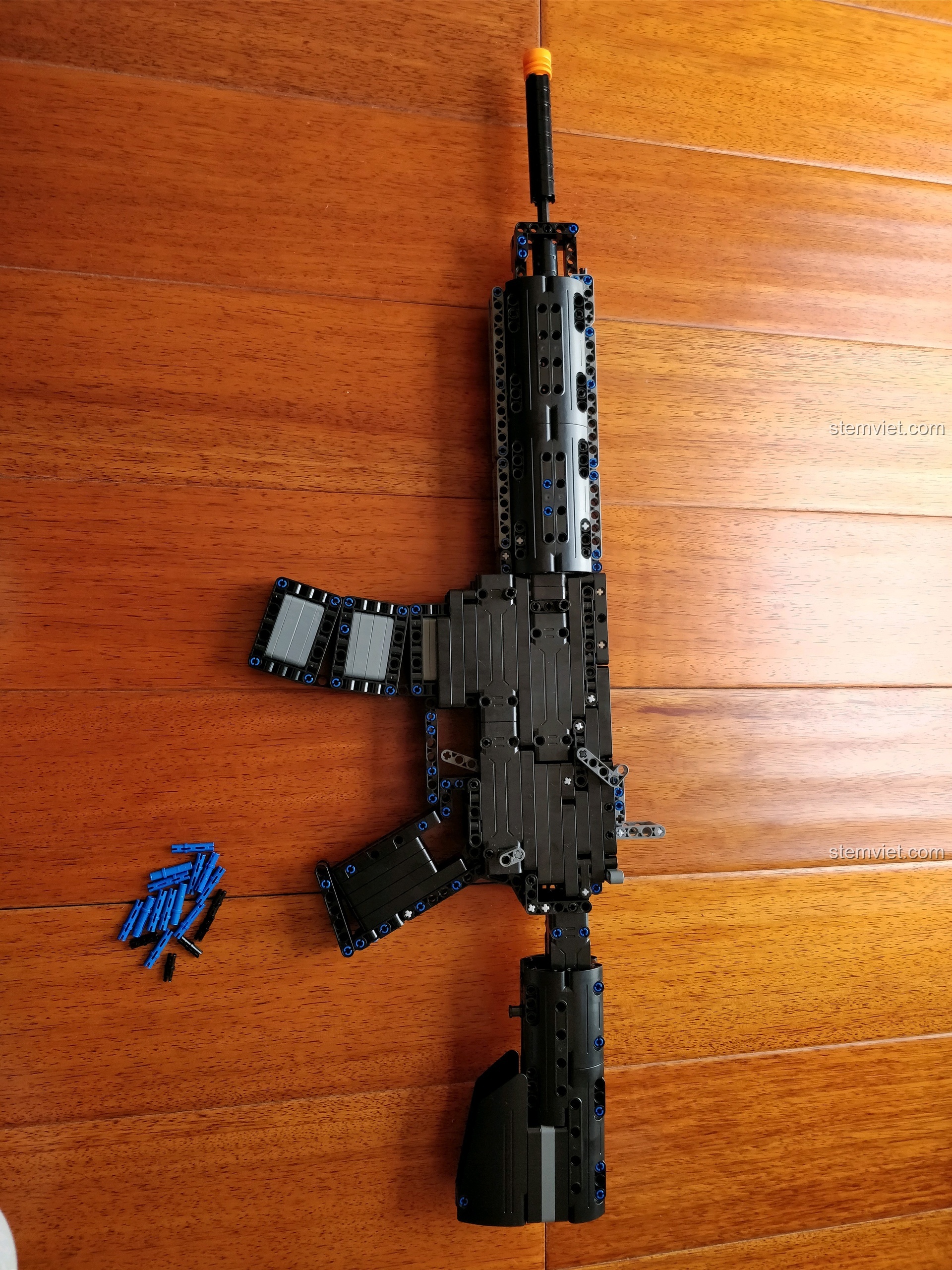 Mô hình súng M4A1 CaDA C81005 hoàn chỉnh nhìn từ trên xuống và một vài chi tiết chốt pin còn thừa lại.