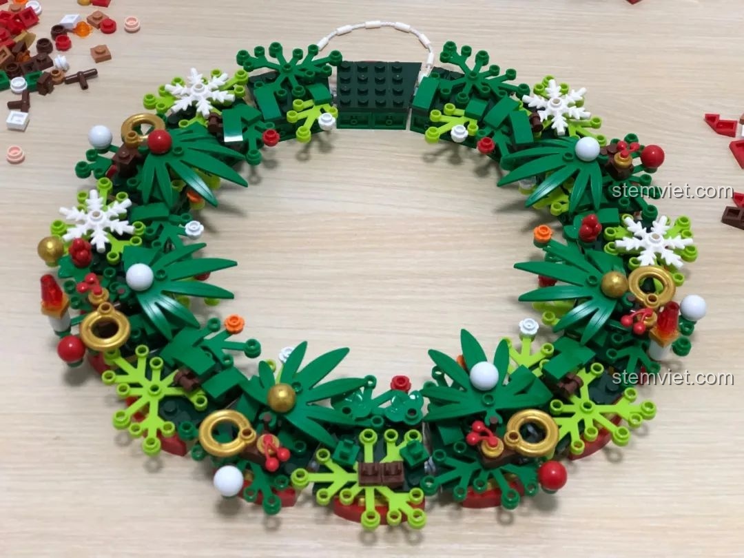 Thêm các chi tiết trang trí như bông tuyết và vòng vàng cho đồ chơi xếp hình Vòng Hoa Giáng Sinh Đa Sắc JAKI JK5118.