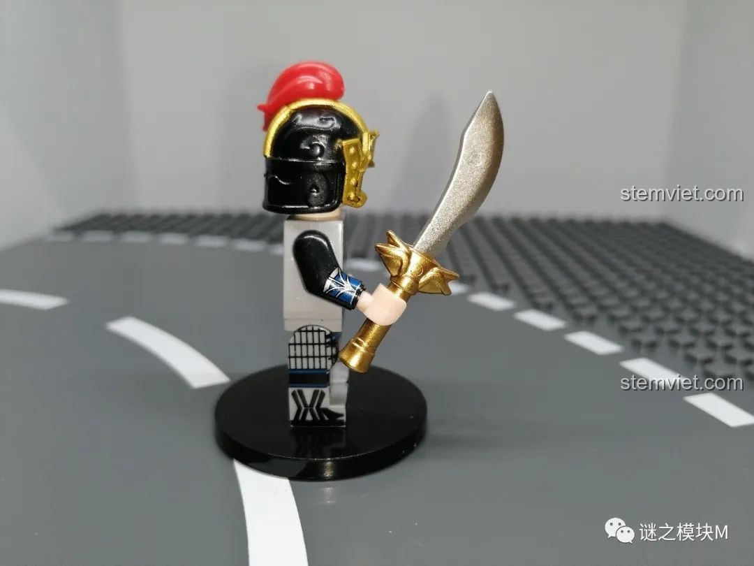 Góc nhìn từ bên cạnh của minifigure Hạ Hầu Đôn, tập trung vào chi tiết thanh đao với phần chuôi mạ vàng và lưỡi bạc.