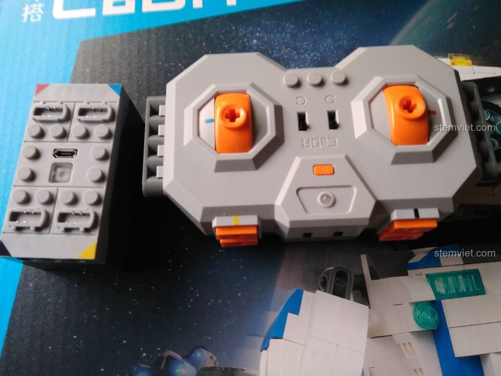 Bộ điều khiển robot CaDA C51027 và bộ thu tín hiệu, cho thấy thiết kế hiện đại và các nút chức năng.