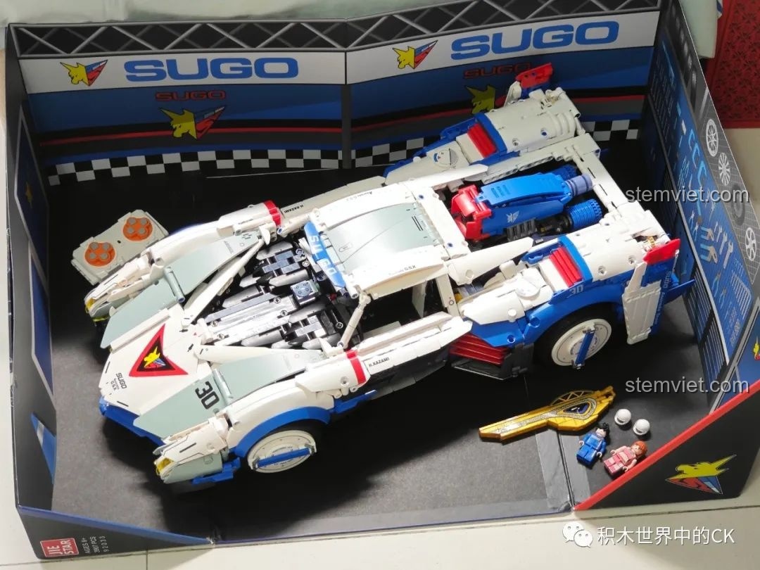 Mô hình JIESTAR 92033 được trưng bày bên trong hộp với bối cảnh garage của đội đua SUGO.