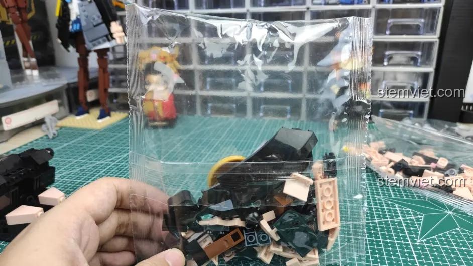 Một túi linh kiện trong tay, cho thấy các mảnh ghép màu đen và nâu của bộ lắp ghép Sluban M38-B1009 Mô hình Trư Bát Giới.
