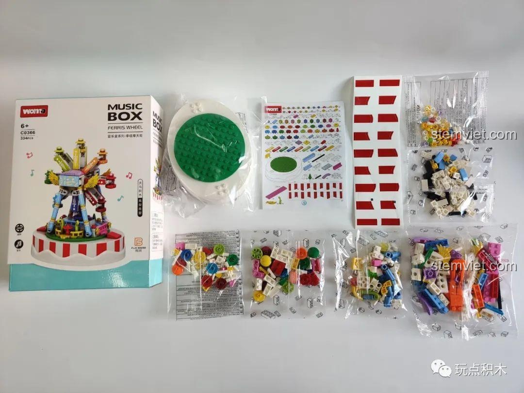 Mở hộp bộ lắp ráp WOMA C0366 Hộp Nhạc Vòng Quay Hạnh Phúc, với các chi tiết nhiều màu sắc và đế trắng.